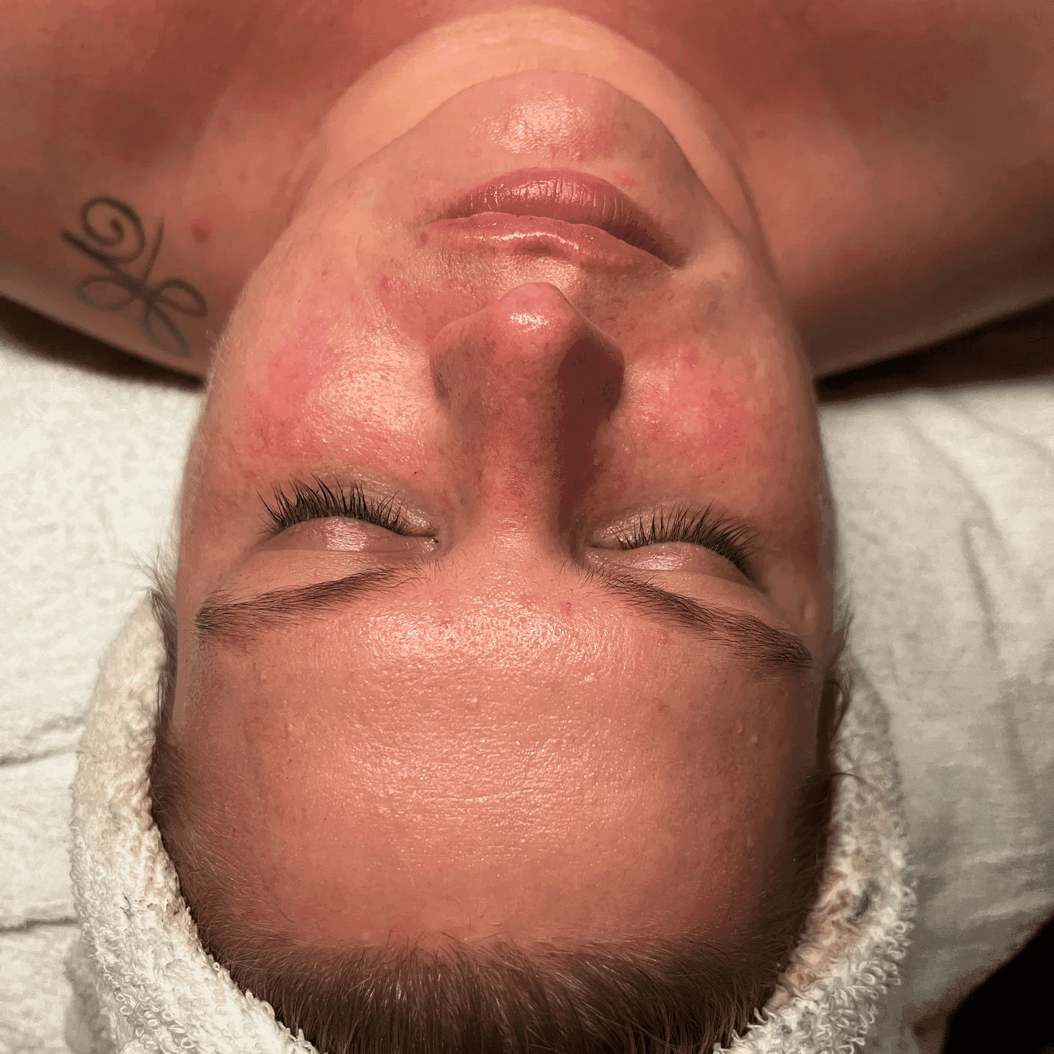 Person with a white headband undergoing a facial treatment, showing a close-up of their face.