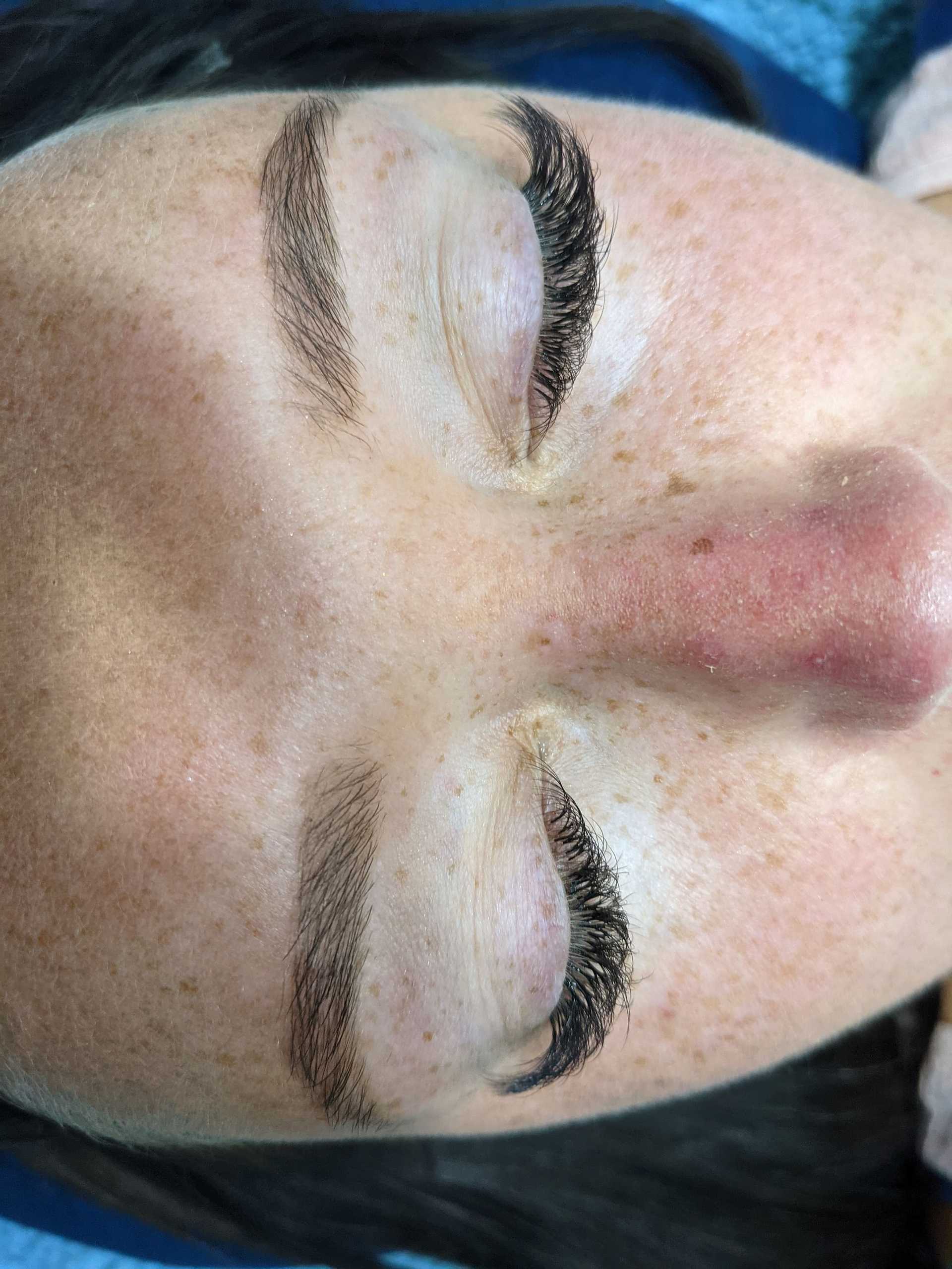 Person with closed eyes showing freshly done eyelash extensions and groomed eyebrows.